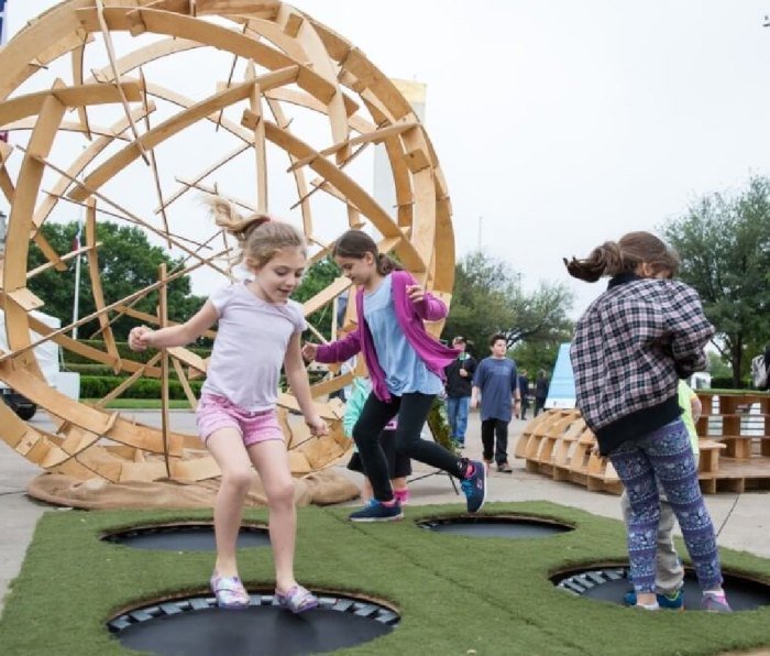 Children playing outside by a large wooden globe at EarthX in Dallas, TX