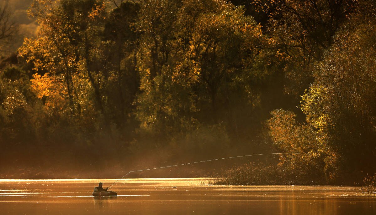 Late afternoon sunlight bathes a fisherman at Lake Wilson in Riverfront Regional Park near Windsor, Friday, Nov. 12, 2021. (Kent Porter / The Press Democrat) 2021