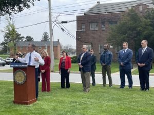 Governor Carney is outside standing at a podium with other leaders standing behind him.