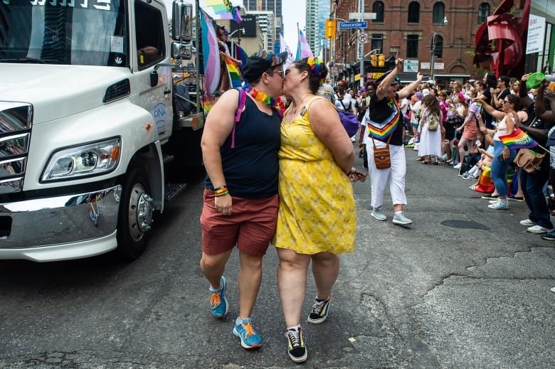 Two people kiss as they walk in the Pride parade, marking the return of in-person festivities for the annual LGBTQ celebration, in Toronto, Sunday, June 26, 2022. THE CANADIAN PRESS/Eduardo Lima