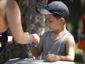 Bennett Demchuk braids a bracelet at a Métis yarn weaving booth during Canada Day celebrations at the Government House grounds on July 1, 2022 in Regina.