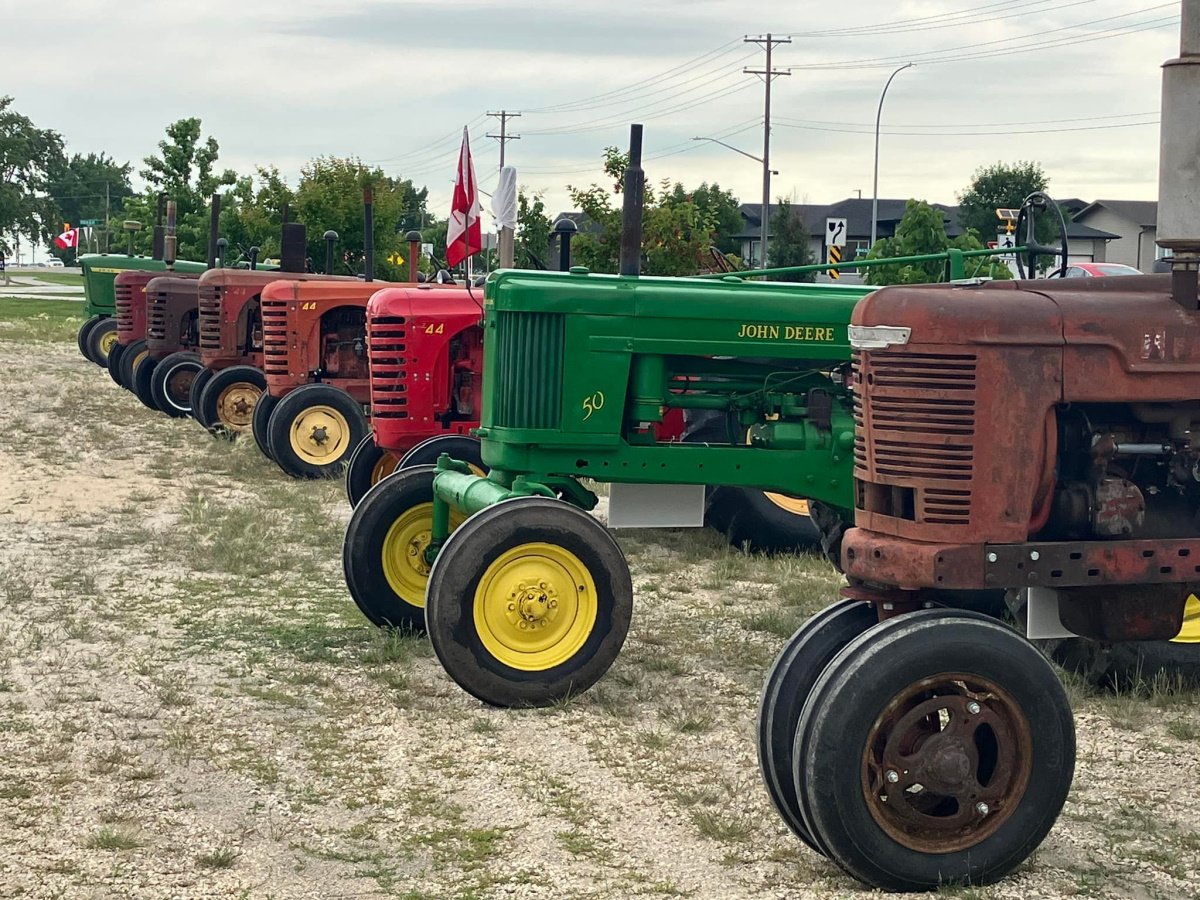 A number of vintage tractors are lined up in a straight row.