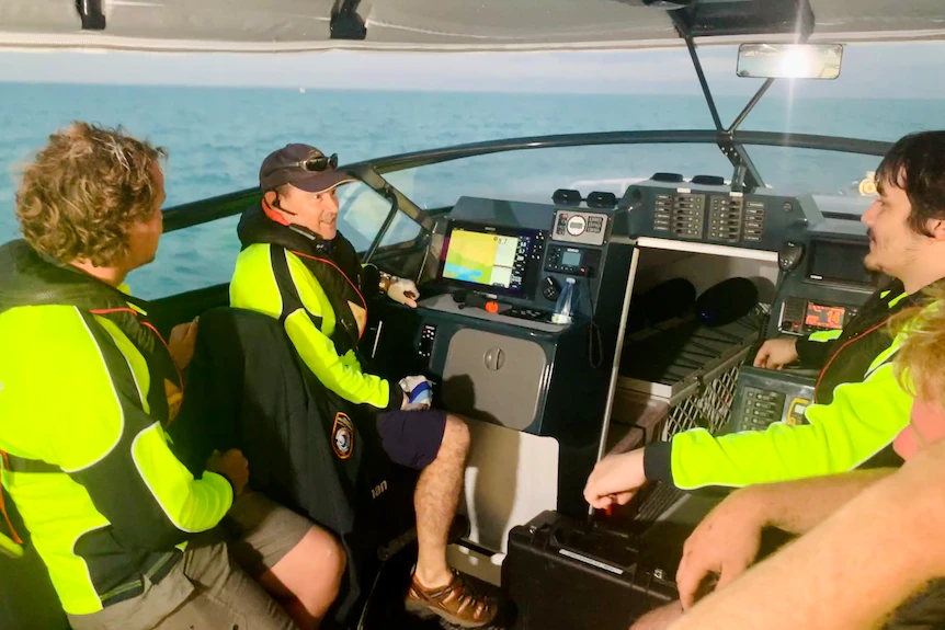 A group of men in fluro shirts sit in a boat.