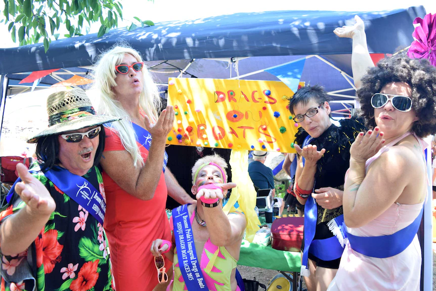 A group of drag queens blows kisses and laughs.